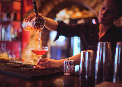 Young female bartender pouring cocktails in a cocktail bar