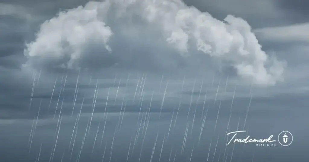 Atmospheric overcast sky with soft rain clouds over a scenic horizon featuring the Trademark Venues logo.